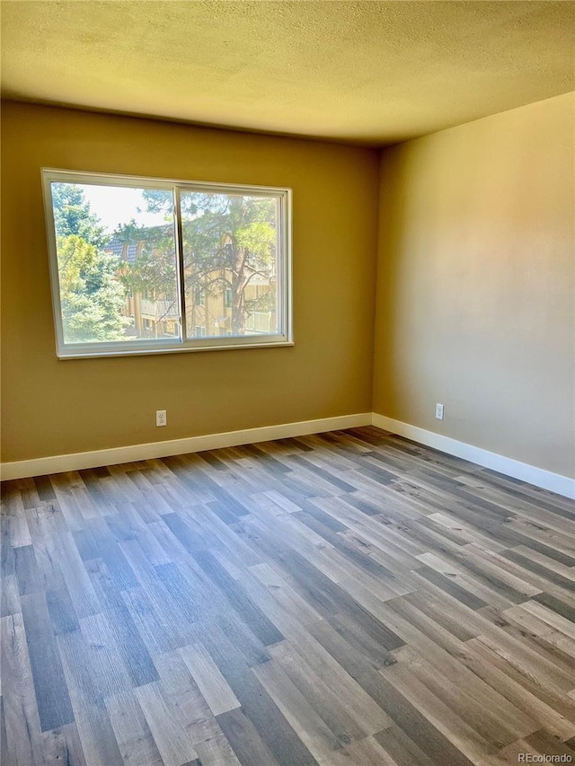 spare room with hardwood / wood-style flooring, a healthy amount of sunlight, and a textured ceiling