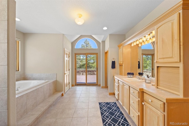 bathroom featuring baseboards, a textured ceiling, vanity, tile patterned floors, and a garden tub