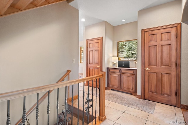 hall with light tile patterned flooring, an upstairs landing, and recessed lighting