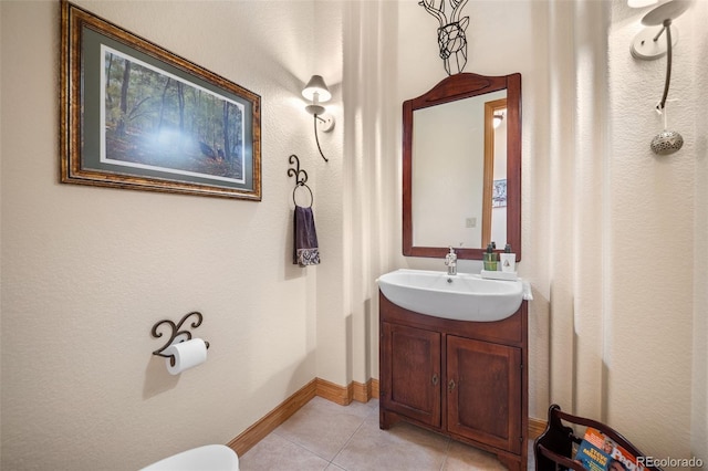 bathroom featuring toilet, tile patterned floors, vanity, and baseboards