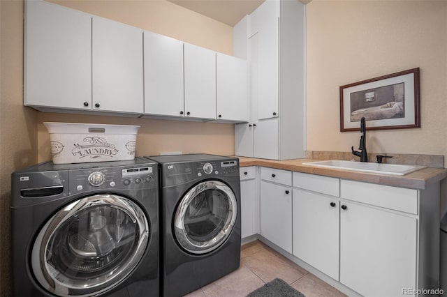 clothes washing area featuring light tile patterned floors, washing machine and dryer, a sink, and cabinet space