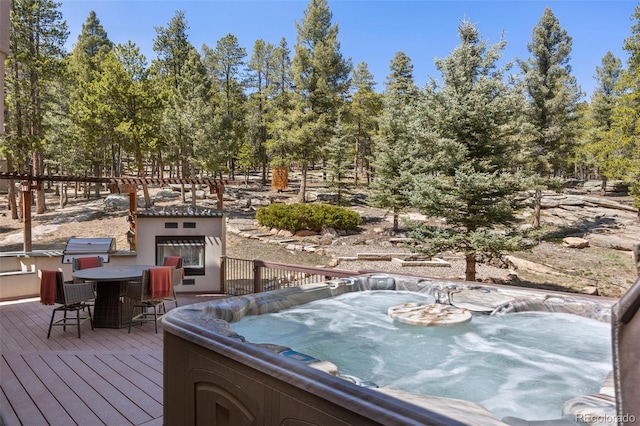 deck with a grill, outdoor dining area, and a hot tub