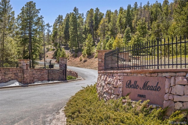 community / neighborhood sign featuring aphalt driveway and fence