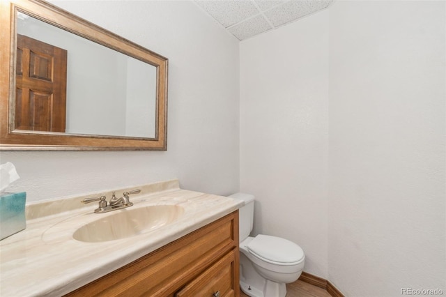 bathroom with vanity, toilet, and a paneled ceiling