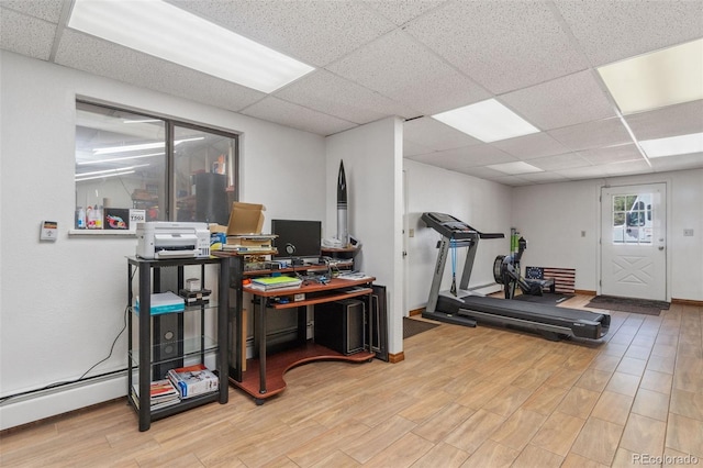 workout room featuring a baseboard heating unit, hardwood / wood-style floors, and a paneled ceiling