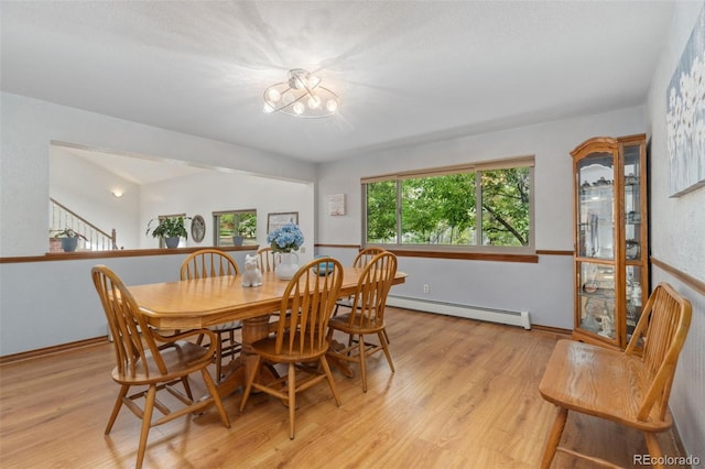 dining space featuring a notable chandelier, light hardwood / wood-style floors, and a baseboard radiator