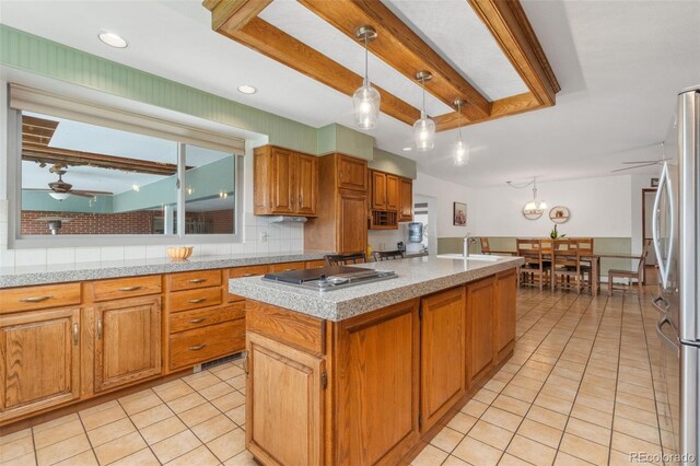 kitchen with stainless steel appliances, beamed ceiling, tasteful backsplash, hanging light fixtures, and a kitchen island