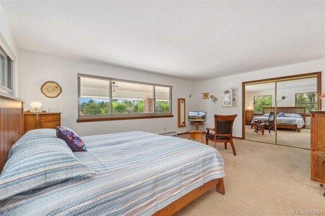 bedroom featuring a baseboard radiator, light colored carpet, and a closet