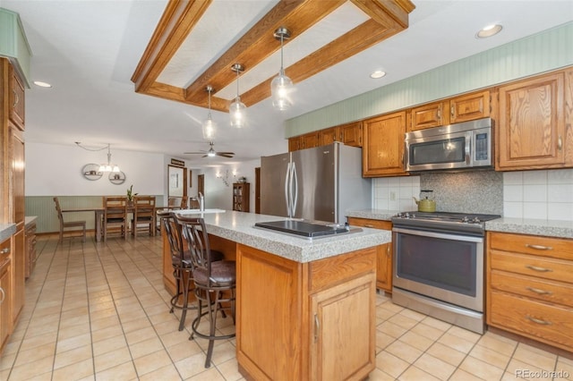 kitchen featuring stainless steel appliances, tasteful backsplash, ceiling fan, a kitchen island, and pendant lighting