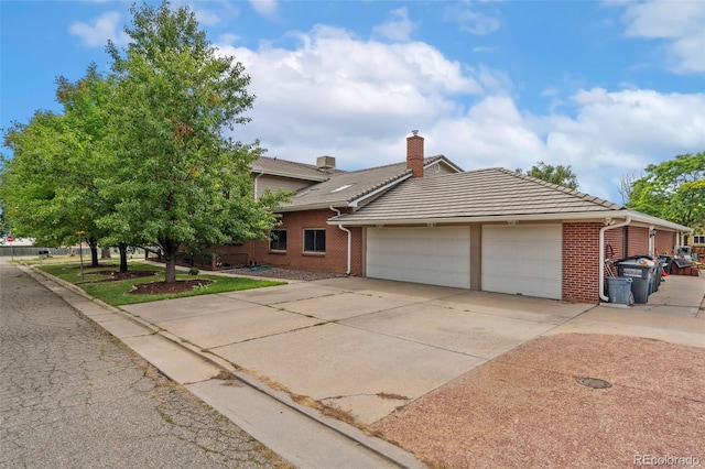 10101 W 72nd Ave, Arvada, CO 80005 - view of front facade featuring brick siding, driveway, an attached garage, and a chimney
