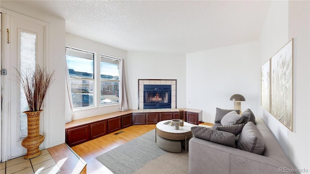 living room featuring a fireplace, a textured ceiling, and light wood-type flooring