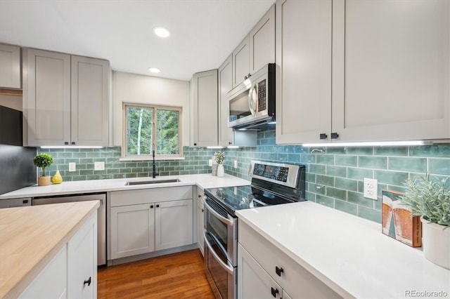 11457 Nancys Dr, Conifer, CO 80433 - kitchen with stainless steel appliances, light countertops, decorative backsplash, gray cabinetry, and light wood-type flooring