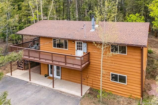 11457 Nancys Dr, Conifer, CO 80433 - back of house featuring a patio, a wooden deck, a shingled roof, and a forest view