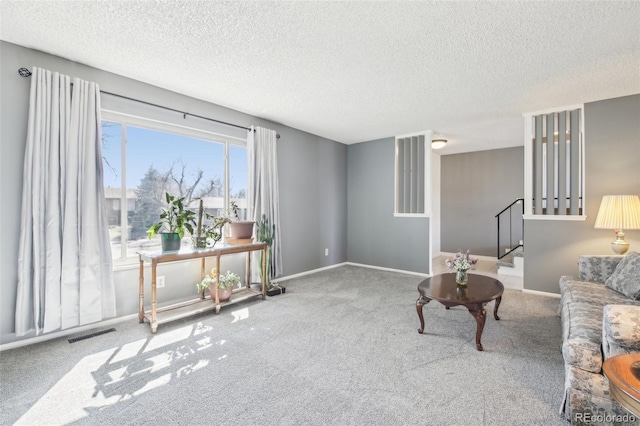 carpeted living room featuring stairs, a textured ceiling, visible vents, and baseboards