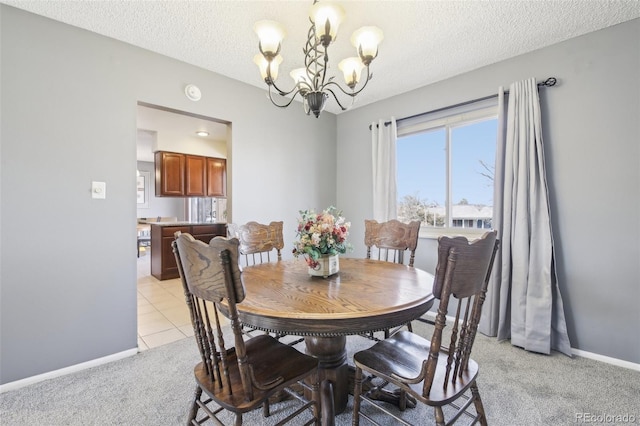 dining area featuring light carpet, light tile patterned floors, baseboards, a textured ceiling, and a chandelier