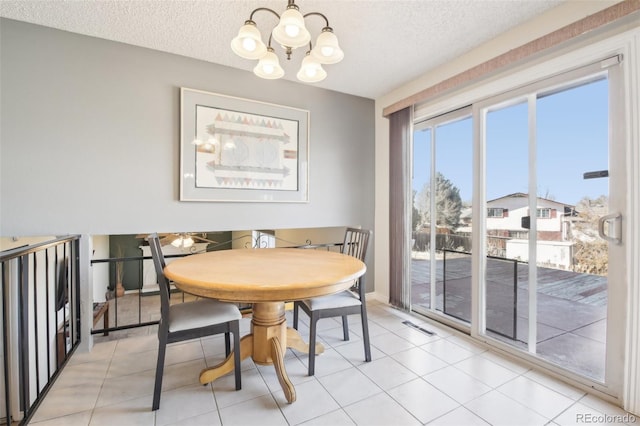 dining area featuring light tile patterned floors, visible vents, baseboards, a textured ceiling, and a notable chandelier