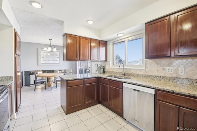 kitchen featuring a sink, appliances with stainless steel finishes, decorative backsplash, light stone countertops, and an inviting chandelier