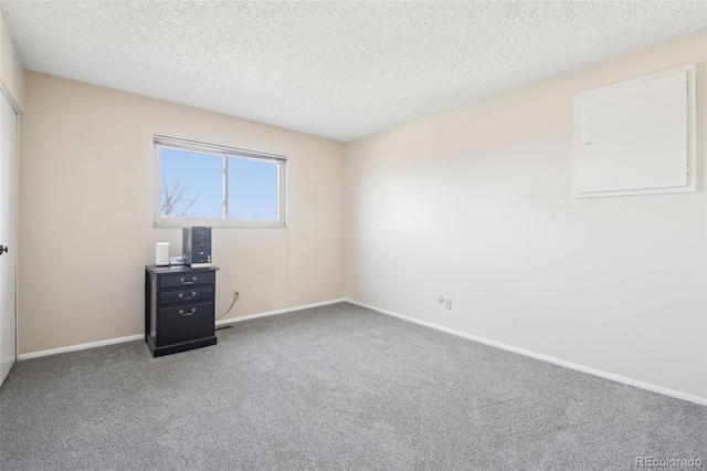 carpeted empty room featuring baseboards and a textured ceiling