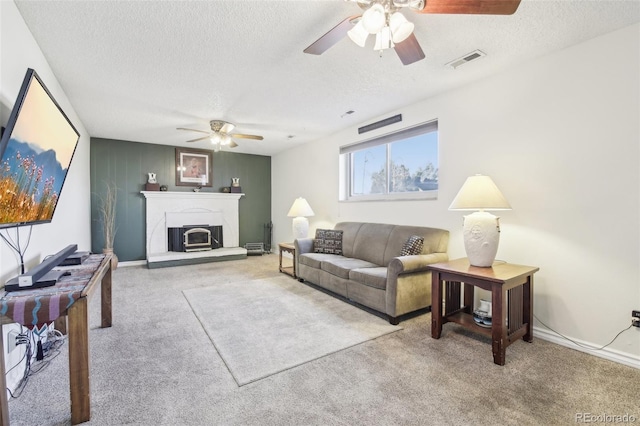 living room with carpet, visible vents, a textured ceiling, and a glass covered fireplace