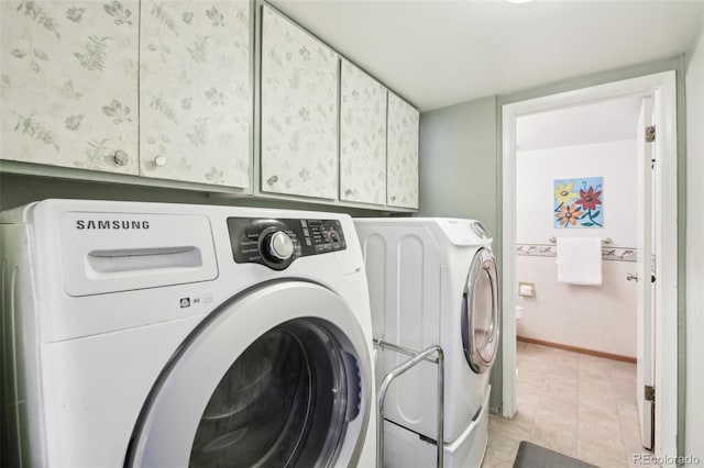 washroom featuring washing machine and dryer, cabinet space, and baseboards