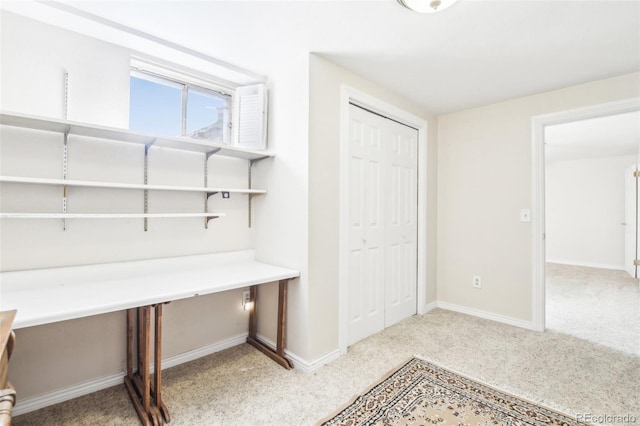 unfurnished office with baseboards and light colored carpet