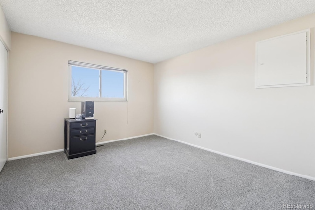 carpeted empty room with a textured ceiling and baseboards