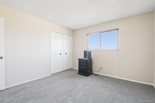 12097 E Mexico Ave, Aurora, CO 80012 - unfurnished bedroom with carpet flooring, a textured ceiling, a closet, and baseboards