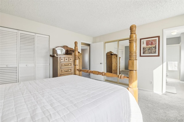 carpeted bedroom with a textured ceiling, multiple closets, and ensuite bath