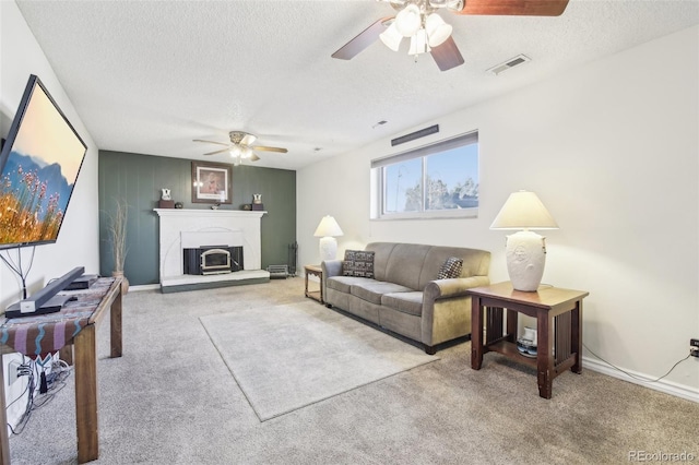 living area with a ceiling fan, carpet, a textured ceiling, a glass covered fireplace, and baseboards