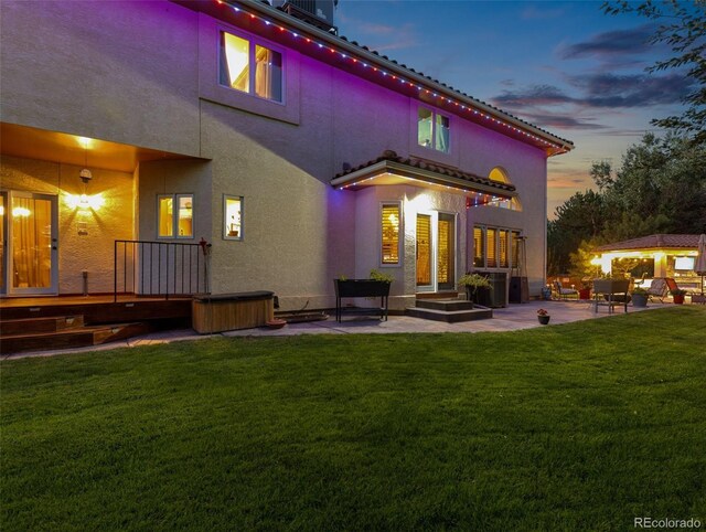 back of property featuring a patio area, a lawn, and stucco siding