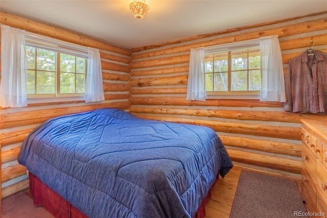 bedroom featuring rustic walls, wood finished floors, and multiple windows