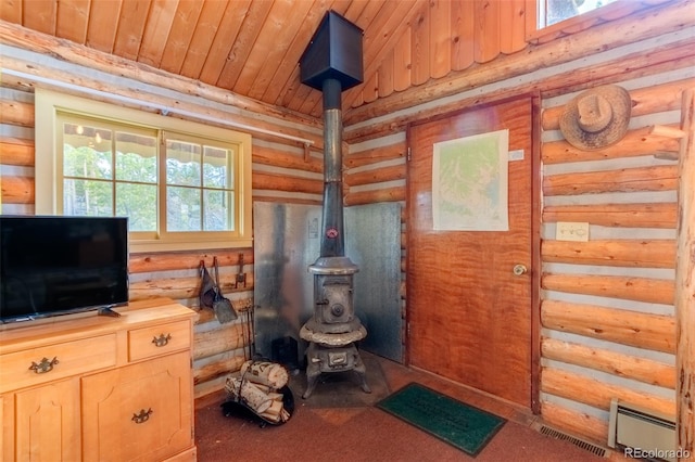 interior space featuring wood ceiling, log walls, a healthy amount of sunlight, and a wood stove
