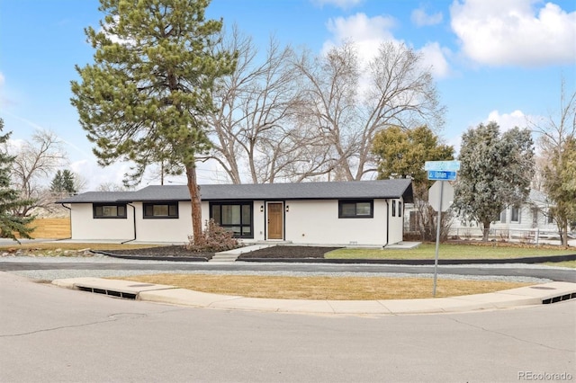 view of front of house with stucco siding, a front lawn, and fence