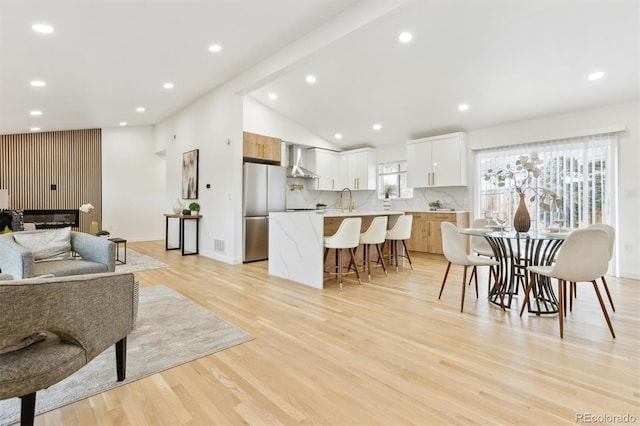 living area with vaulted ceiling, recessed lighting, baseboards, and light wood finished floors