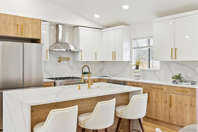 kitchen with lofted ceiling, wall chimney exhaust hood, light stone countertops, and stainless steel appliances