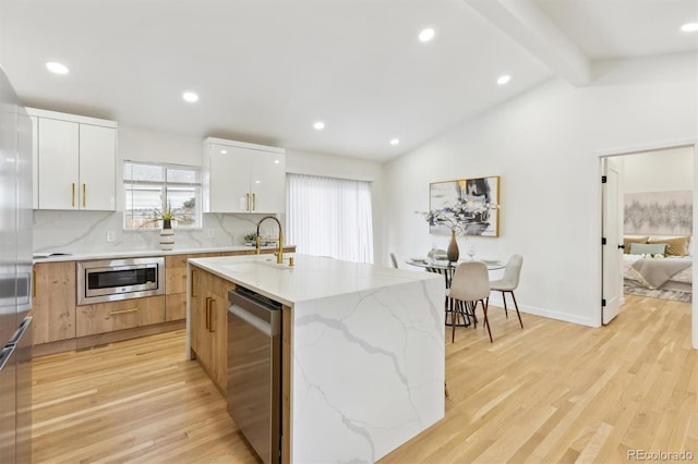 kitchen with tasteful backsplash, modern cabinets, light wood-type flooring, and appliances with stainless steel finishes