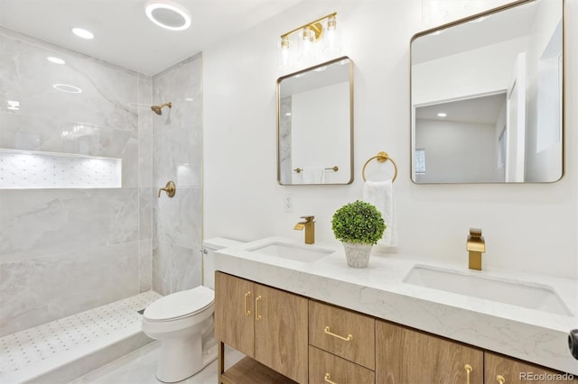 full bathroom featuring double vanity, toilet, a tile shower, and a sink