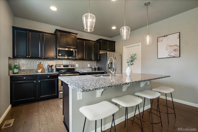 1181 W 170th Ave, Broomfield, CO 80023 - kitchen featuring appliances with stainless steel finishes, dark wood finished floors, backsplash, a breakfast bar area, and recessed lighting
