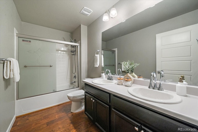 1181 W 170th Ave, Broomfield, CO 80023 - full bathroom featuring toilet, double vanity, combined bath / shower with glass door, and wood finished floors