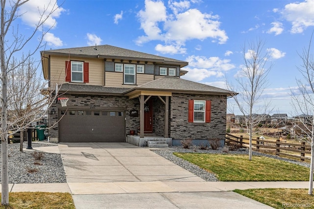 prairie-style house with driveway, a shingled roof, fence, and an attached garage