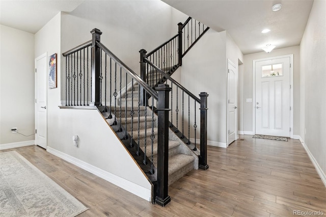 foyer featuring baseboards, stairs, and wood finished floors
