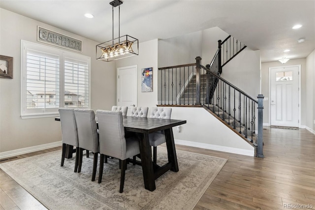 dining area featuring stairway, an inviting chandelier, baseboards, visible vents, and wood finished floors