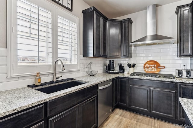 kitchen featuring wall chimney range hood, backsplash, a sink, and stainless steel appliances