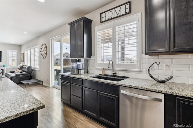 kitchen with decorative backsplash, a sink, stainless steel dishwasher, and wood finished floors