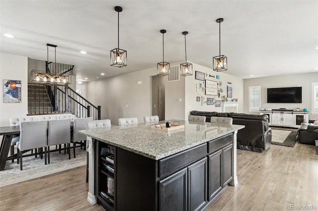 kitchen with light stone countertops, recessed lighting, dark cabinetry, and light wood finished floors