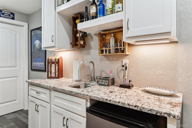 kitchen featuring a sink, open shelves, white cabinetry, light stone countertops, and dishwasher