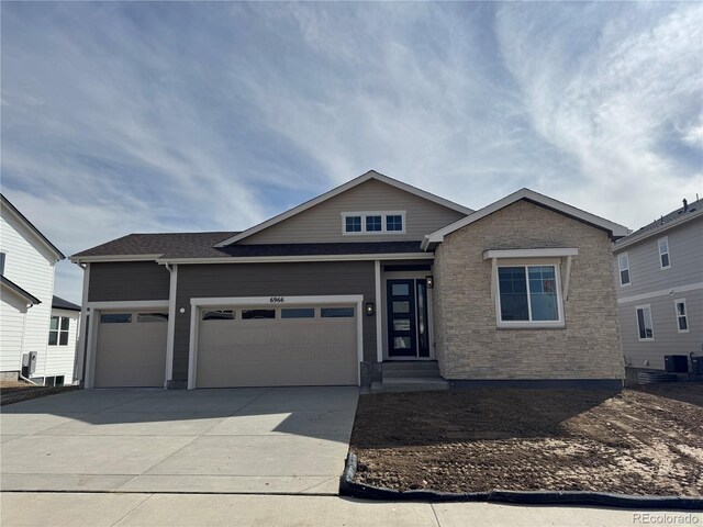 view of front facade featuring a garage, central AC, driveway, and a shingled roof