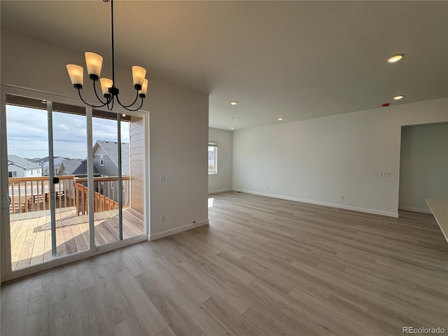 spare room with a chandelier, recessed lighting, light wood-style flooring, and baseboards