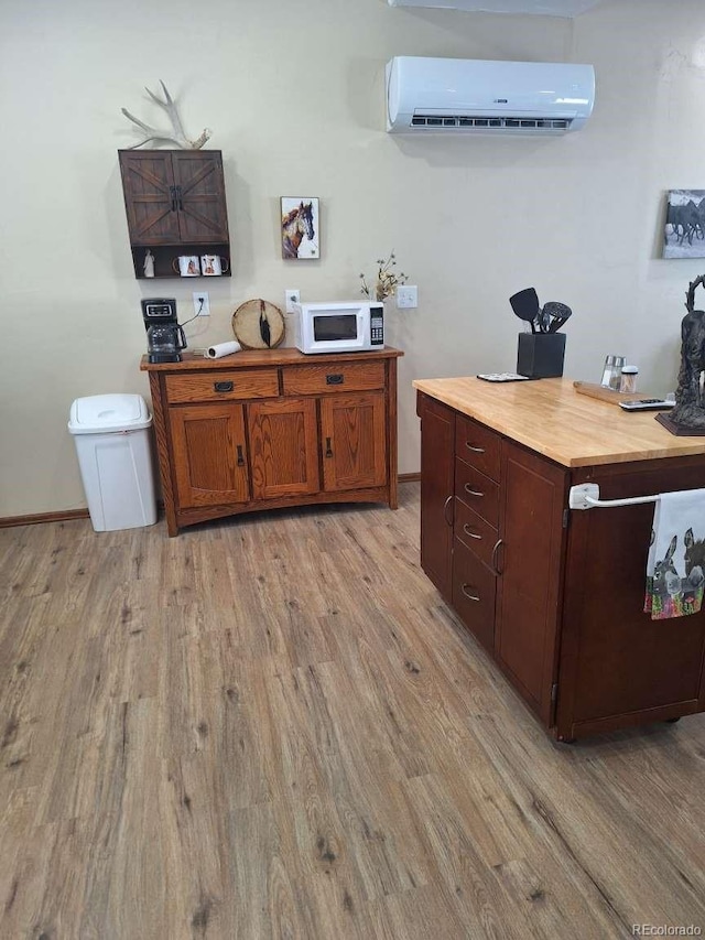 kitchen featuring light wood-type flooring, wood counters, and a wall mounted air conditioner