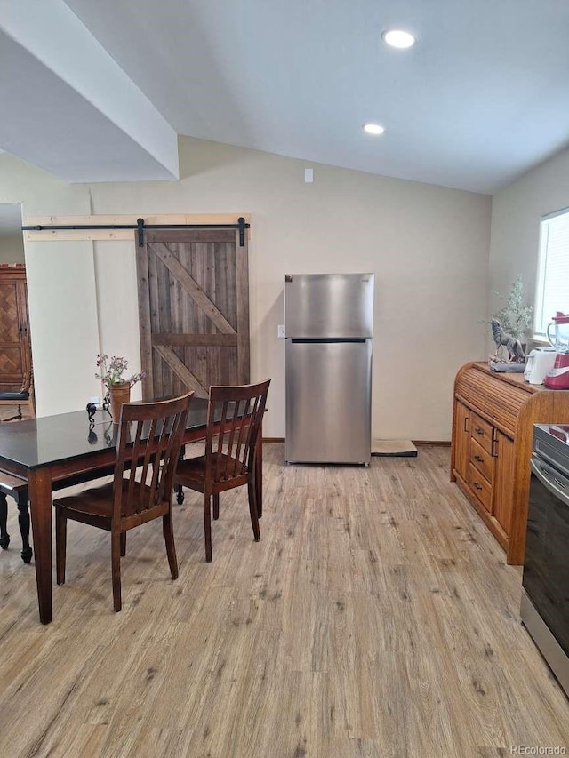 dining area with light wood-type flooring and a barn door